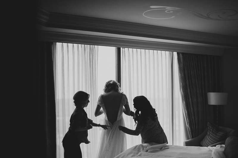 Bride getting into dress flanked by assistants at St Regis Hotel