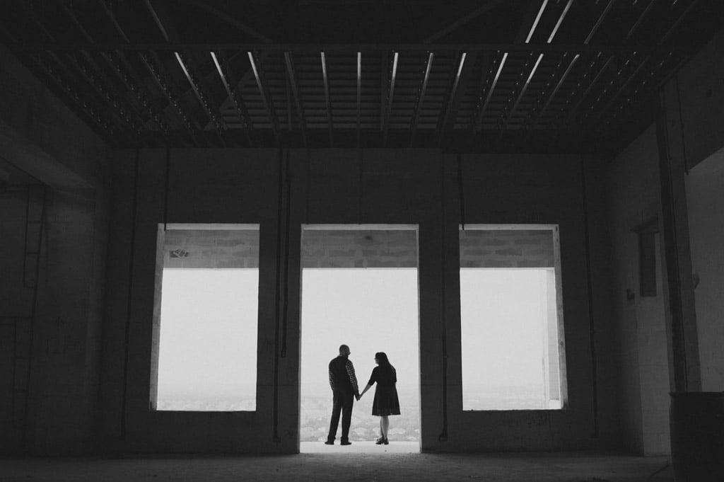 Couple hold hands in structure -San Antonio Engagements