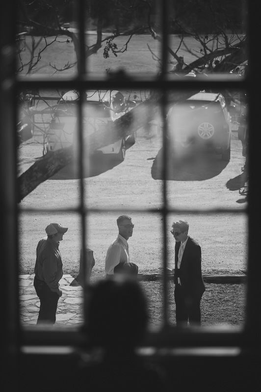 Groomsmen passing window at don strange ranch 