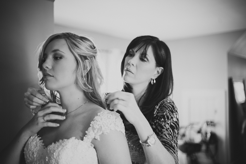 mother of bride places necklace around brides neck