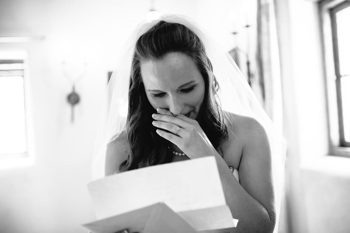 A bride wipes a tear away when reading a letter from her husband to be