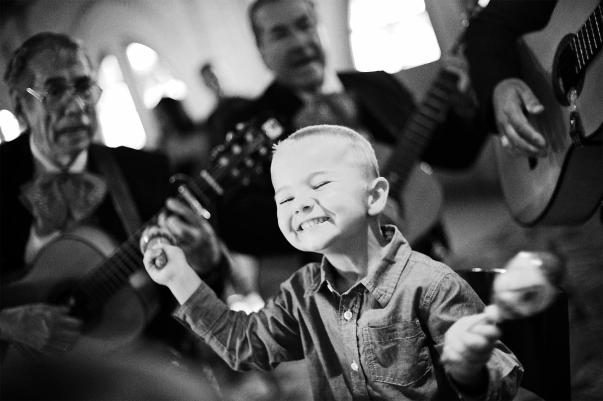 Boy surrounded by mariachi plays his marachas in San Antonio Texas during a wedding reception