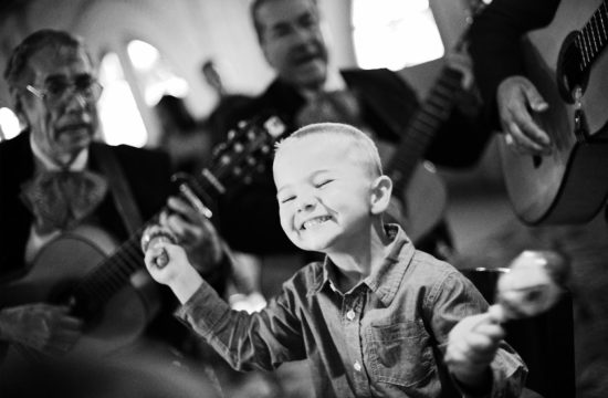 Boy surrounded by mariachi plays his marachas in San Antonio Texas during a wedding reception