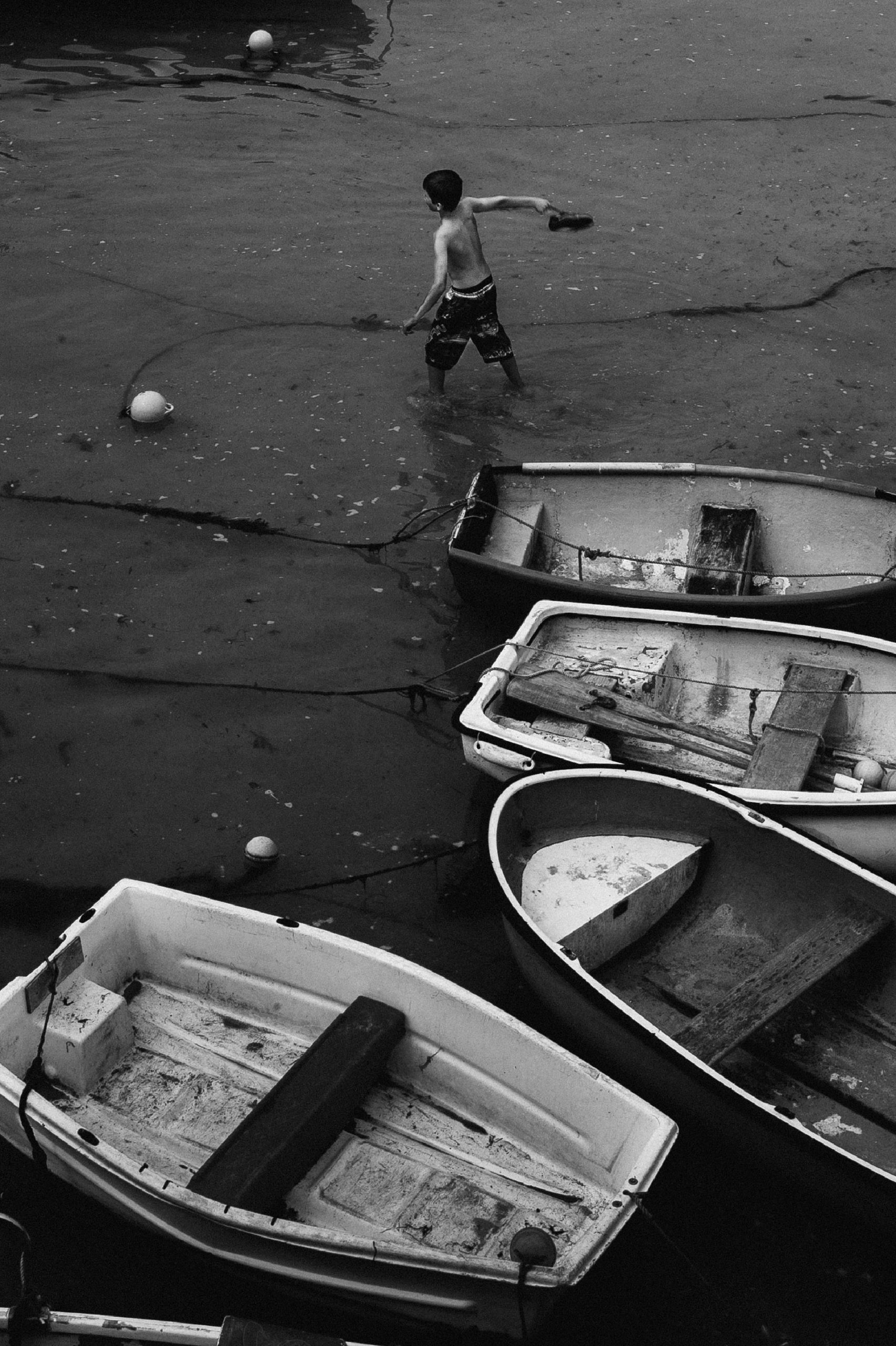 Boy throws shoe in bay Cornwall, England