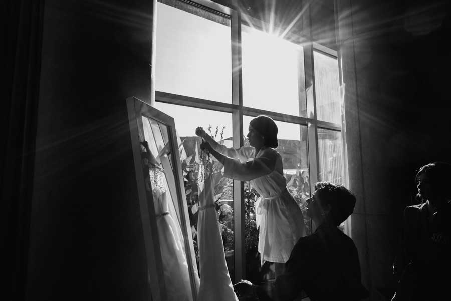 A bride reaches for her dress at a hotel window at W Hotel Austin Brides Hangs Wedding Dress