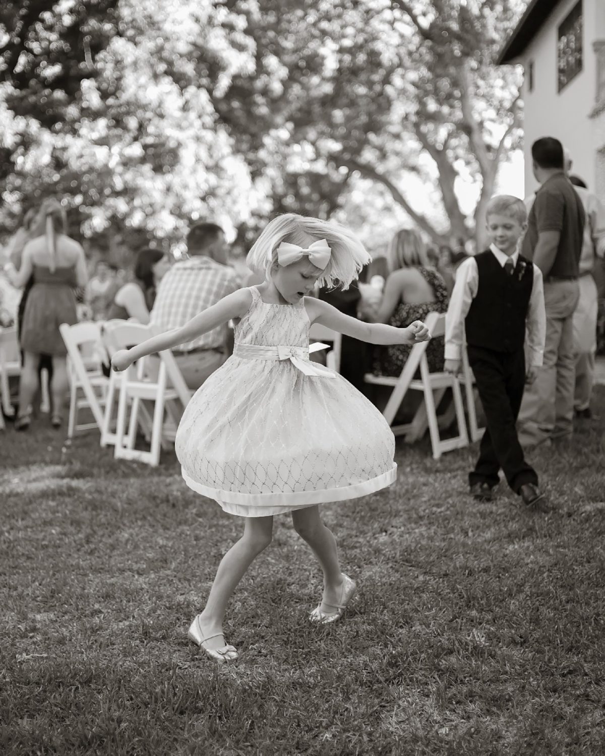 A flower girl twirls at a wedding reception in New Braunfels Texas as a boy watches Leica wedding photographer Philip Thomas