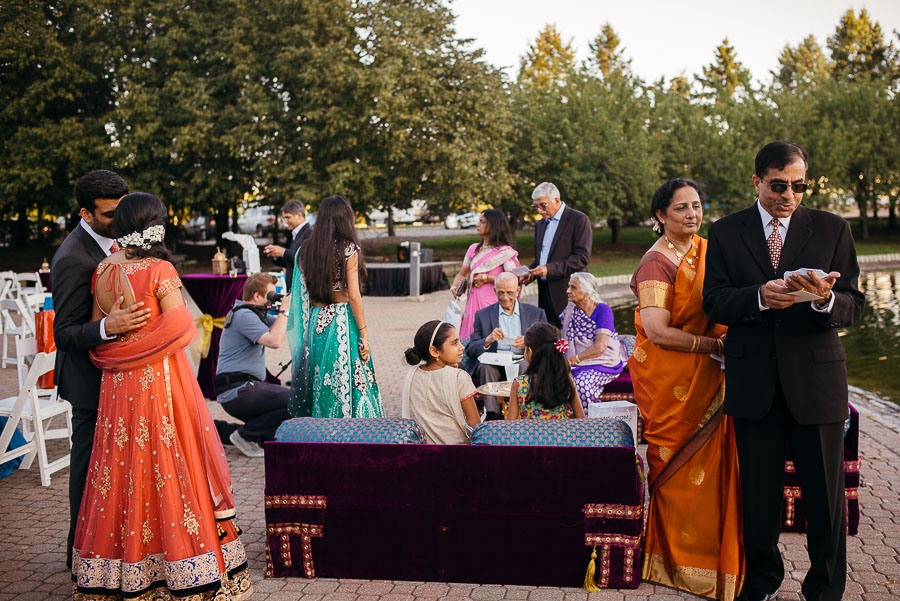 Bride and groom whisper as mother and father opens gift