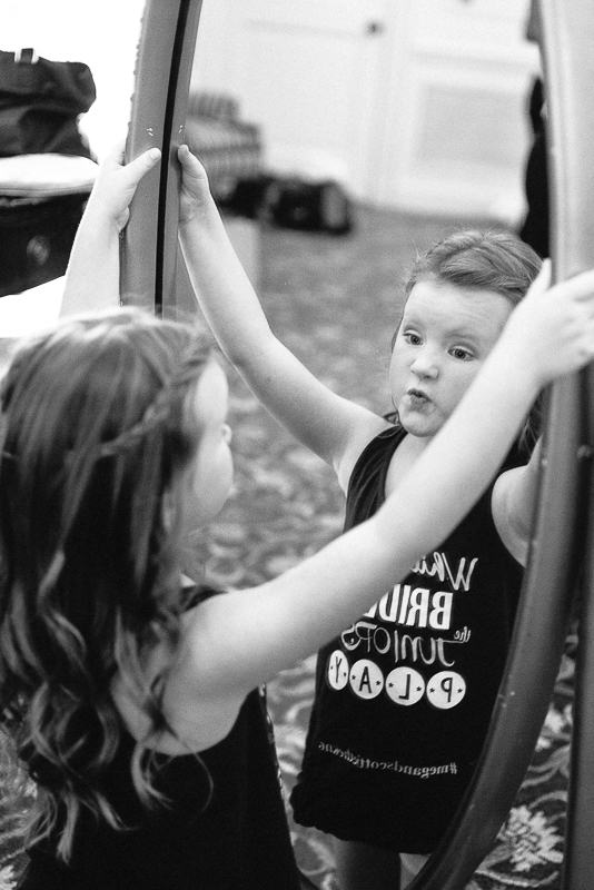 Little girl pulling funny face in mirror unaware of the camera