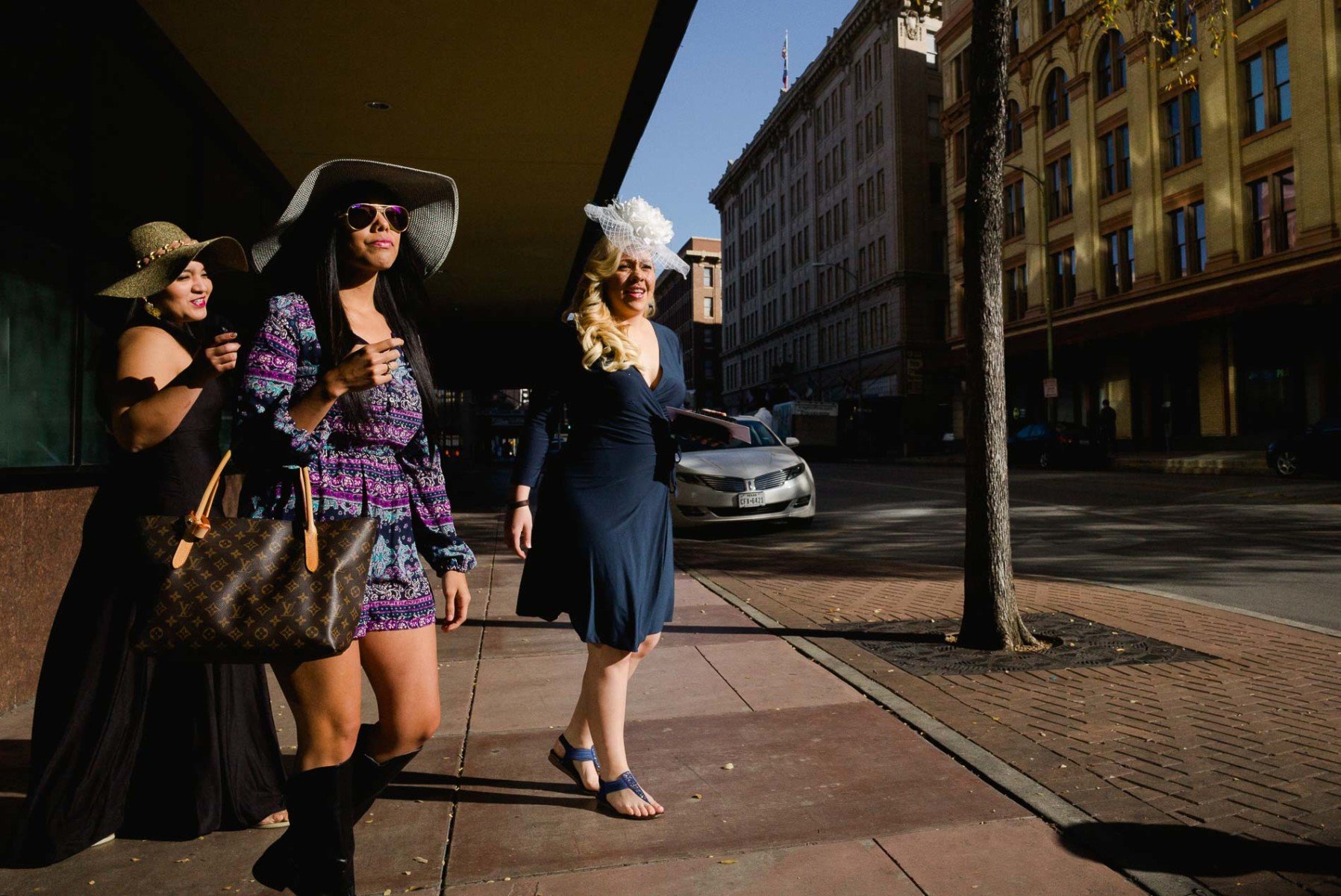 Women walk out from hotel lobby with fiesta hats Leica Street Photography by PHilip Thomas