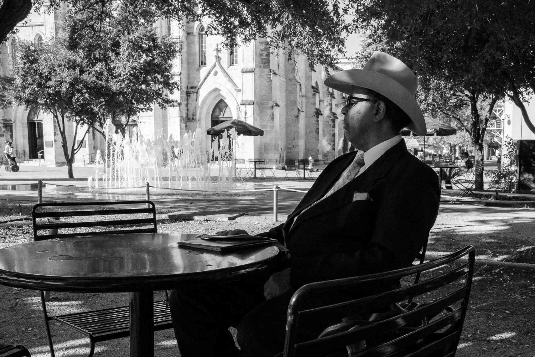 A man dressed in a suit relaxes in Alamo Plaza under some shade Leica Street Photography by PHilip Thomas