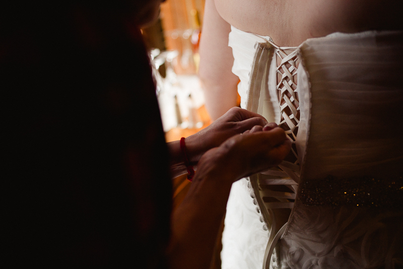 Buttoning up back of brides dress at Welfare Cafe