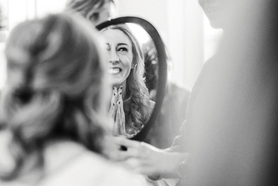 Bride looking delighted after makeup session in mirror