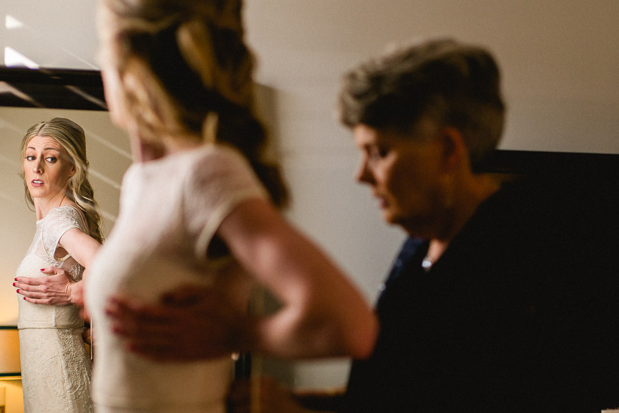 Bride getting ready looking in mirror with mother