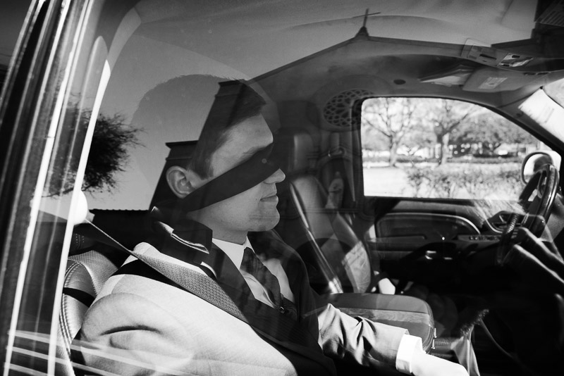 To avoid seeing the bride, groom wears at tie over his eyes while waiting in limo