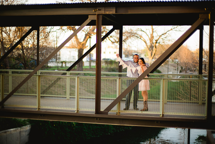 Couple holding save the date on bridge at Pearl Brewey
