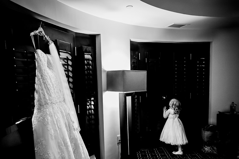 Flowergirl peeks out of window at The Valencia with brides dress in foreground