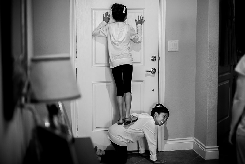 Brides daughters look through the peep hole in front door of home