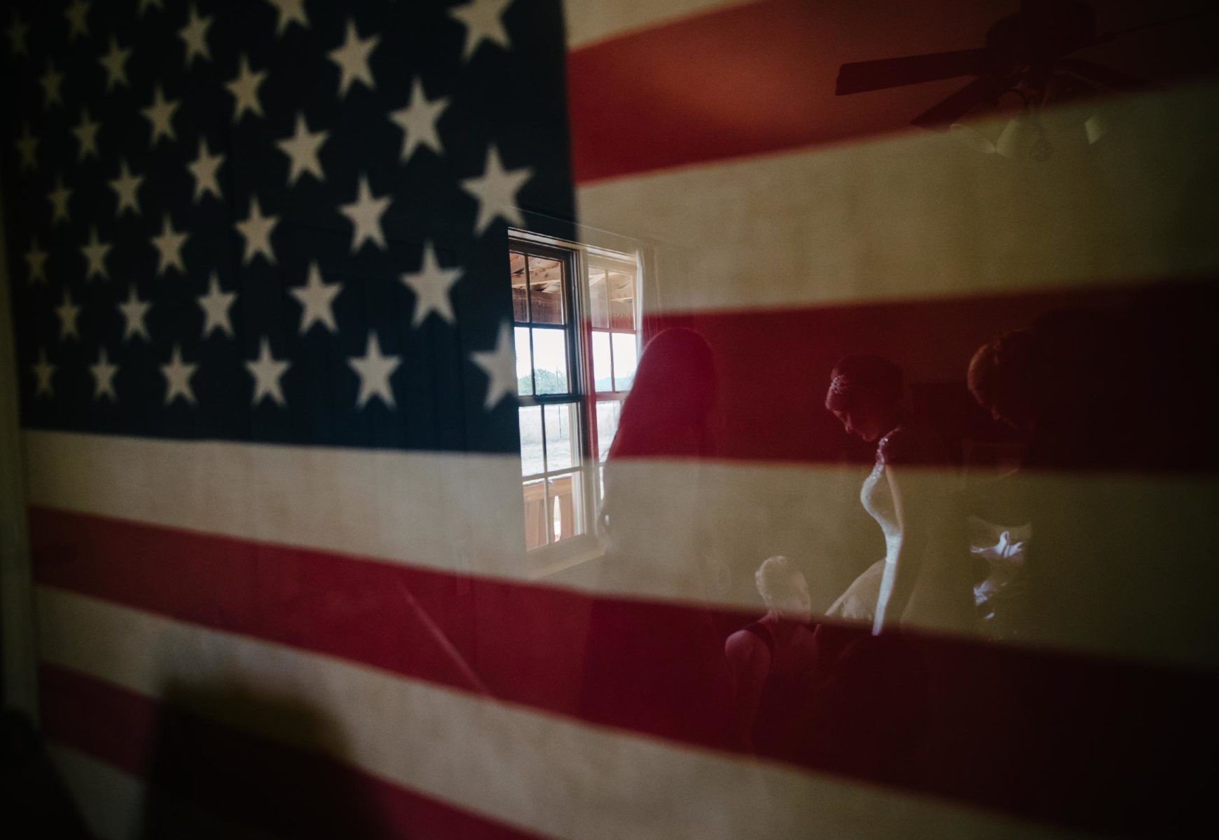 San-Antonio-wedding-photographer-Philip-Thomas captures Bride as she gets ready in reflection of an American flag. Photographed by Philip Thomas with a Leica M.