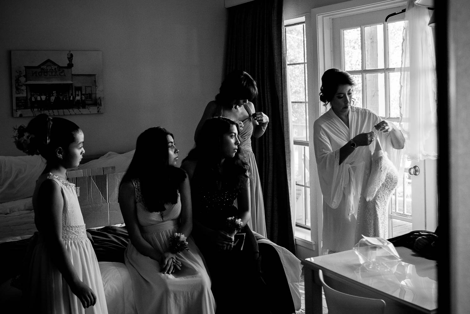 Bridesmaids sit on bed watching bride get ready with her wedding gown at hotel-alsace-wedding-photographer-philip-thomasw