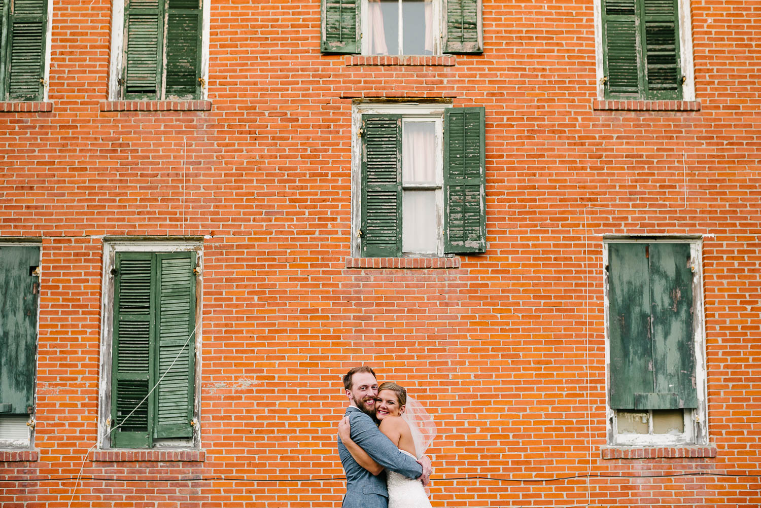 Couple pose hugging against a red orange wall at the-lyceum-wedding-leica-wedding-photographer-philip-thomas