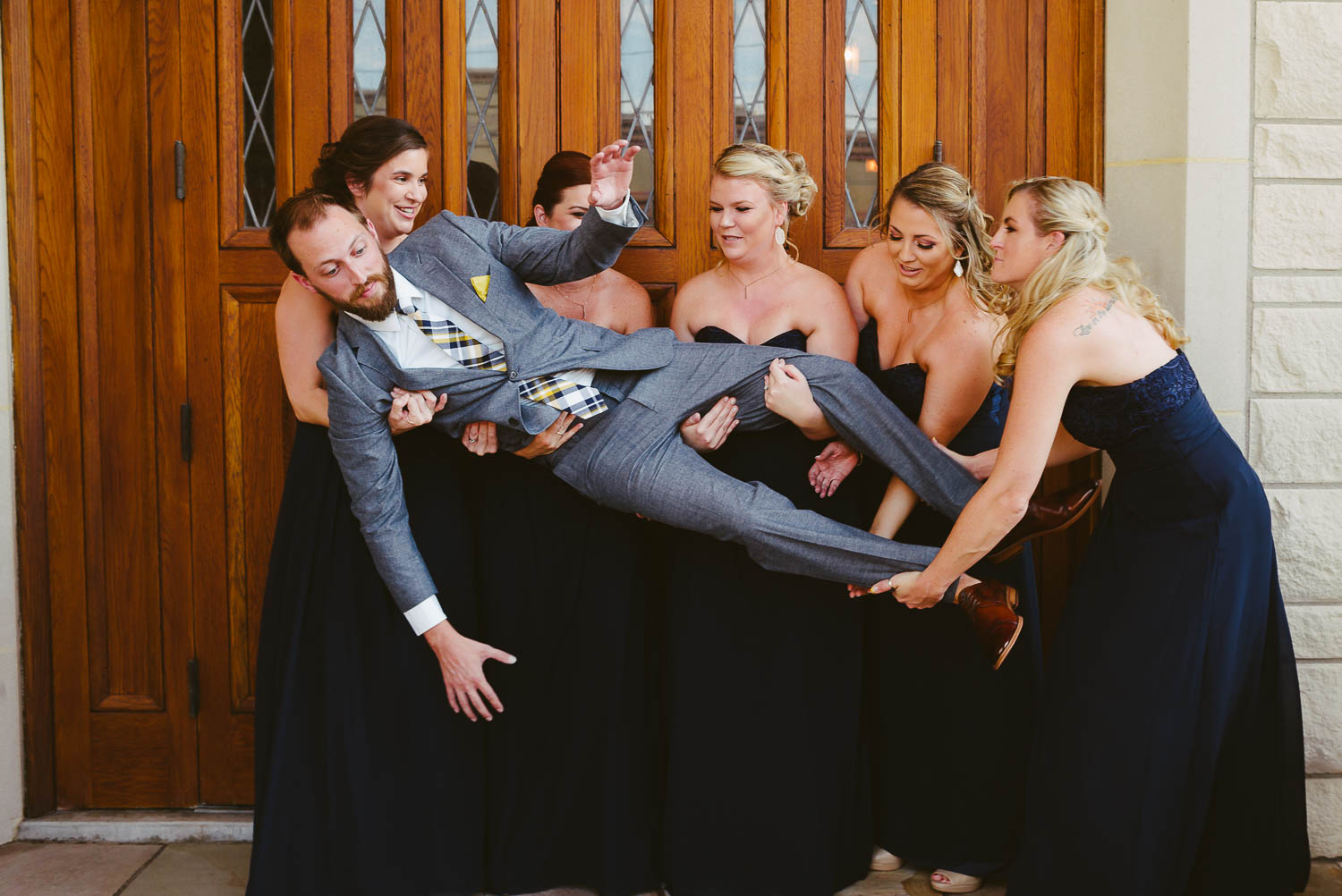 Groom held in the air by bridesmaids at The Lyceum Wedding Galveston Texas