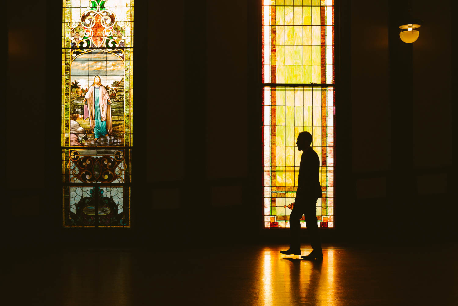 Groom moves past stained glass window as a silhouette at the-lyceum-wedding-leica-wedding-photographer-philip-thomas-022