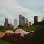 downtown-houston-skyline-engagementshows couple lying in the grass-leica-wedding-photographer-philip-thomas
