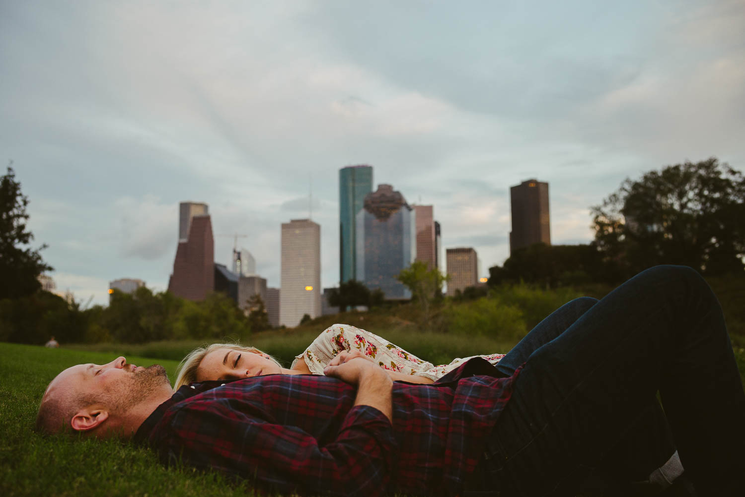 downtown-houston-skyline-engagementshows couple lying in the grass-leica-wedding-photographer-philip-thomas