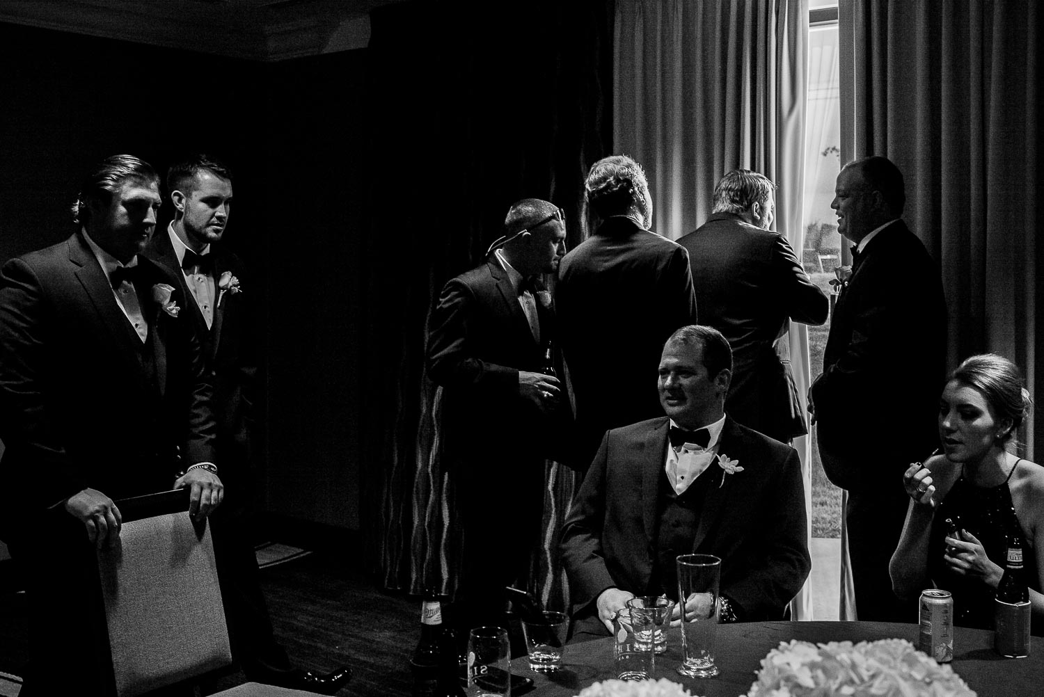 Grooms sits in foreground and some groomsmen look outside through curtains like a scene from The Godfather at La Cantera Resort, San Antonio Texas