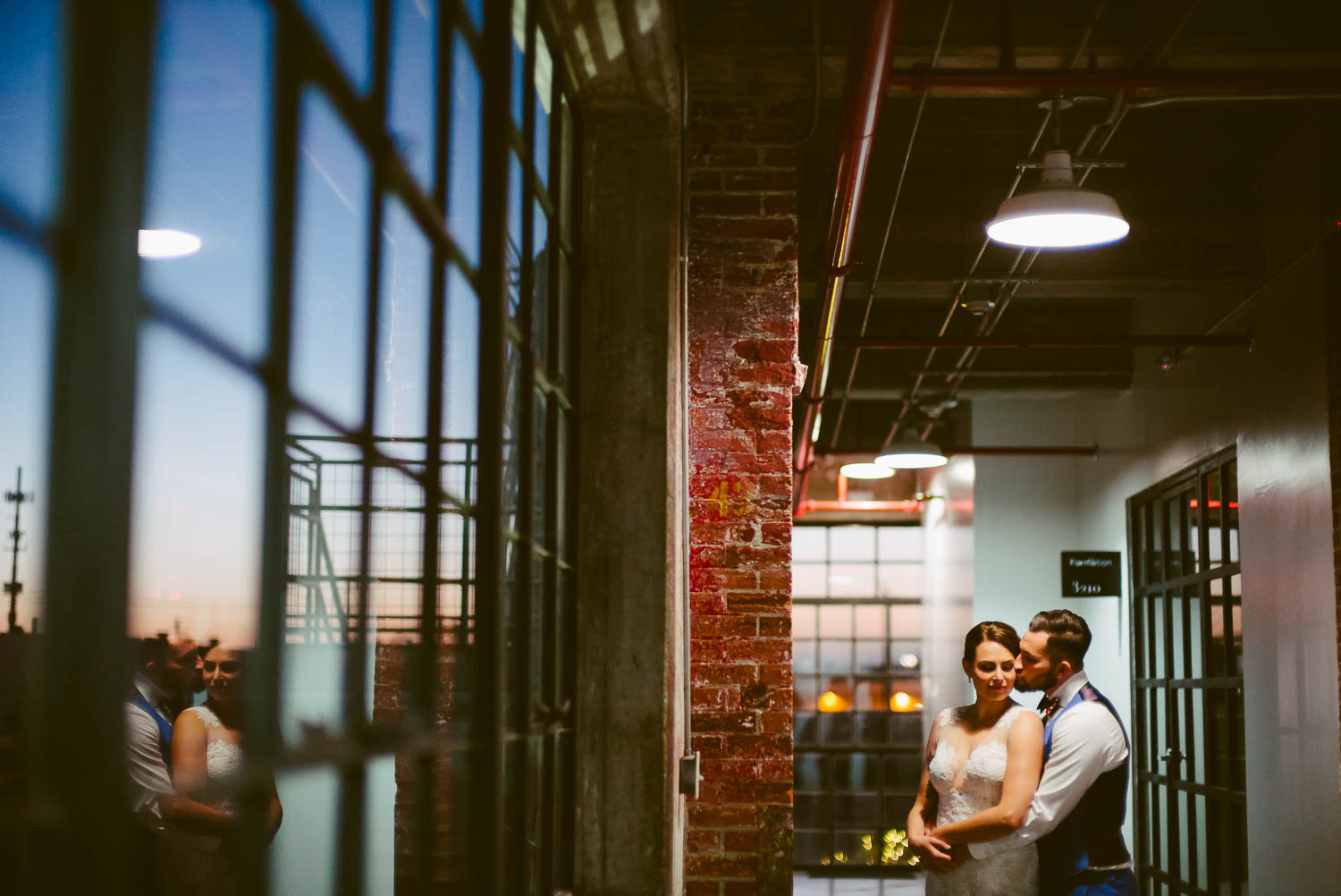 Couple pose on wedding day at The Astorian after sunset with a window reflection, Houston, Texas.