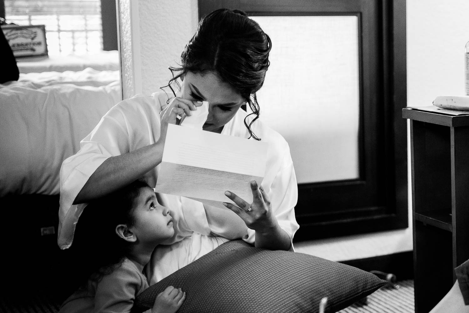 Bride wipes tears reading letter from husband to be with daughter looking up