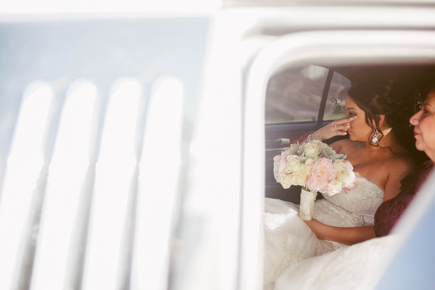 Bride wipes tear away sitting with her mother at immaculate-heart-of-mary-church-philip-thomas-photography