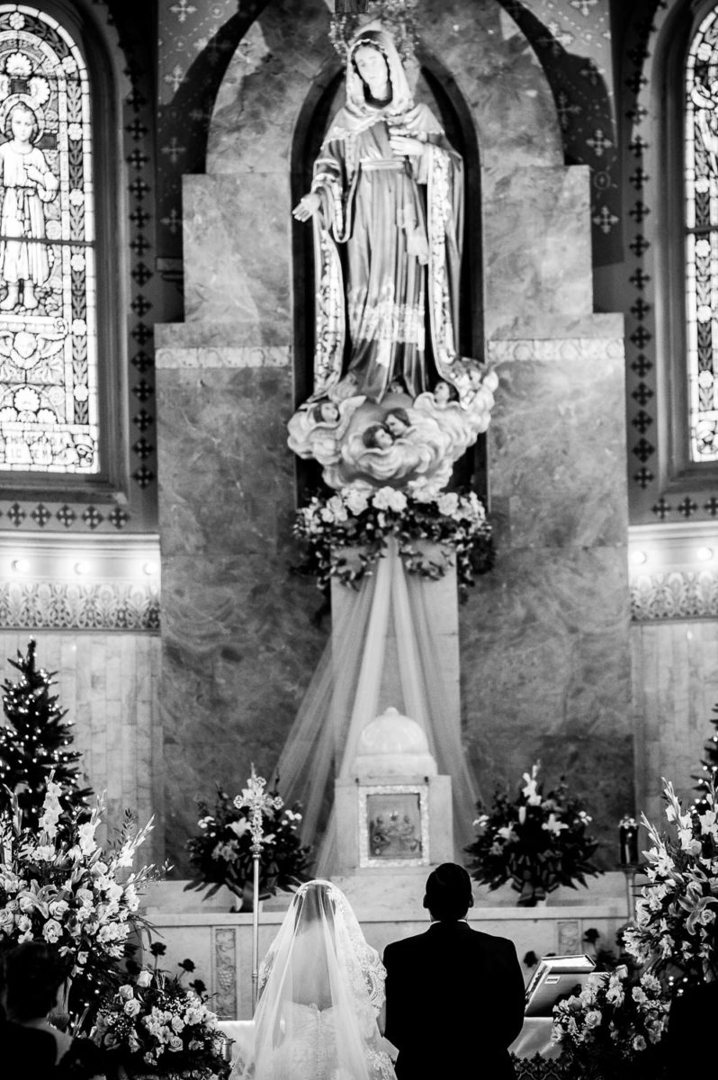 Black and white shot of bride and groom kneeling during wedding at immaculate-heart-of-mary-church-philip-thomas-photography