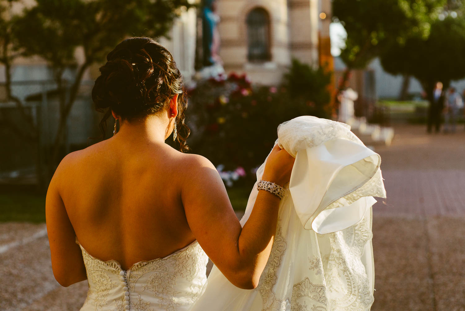 Bride picks trailing wedding dress with hand at immaculate-heart-of-mary-church-philip-thomas-photography