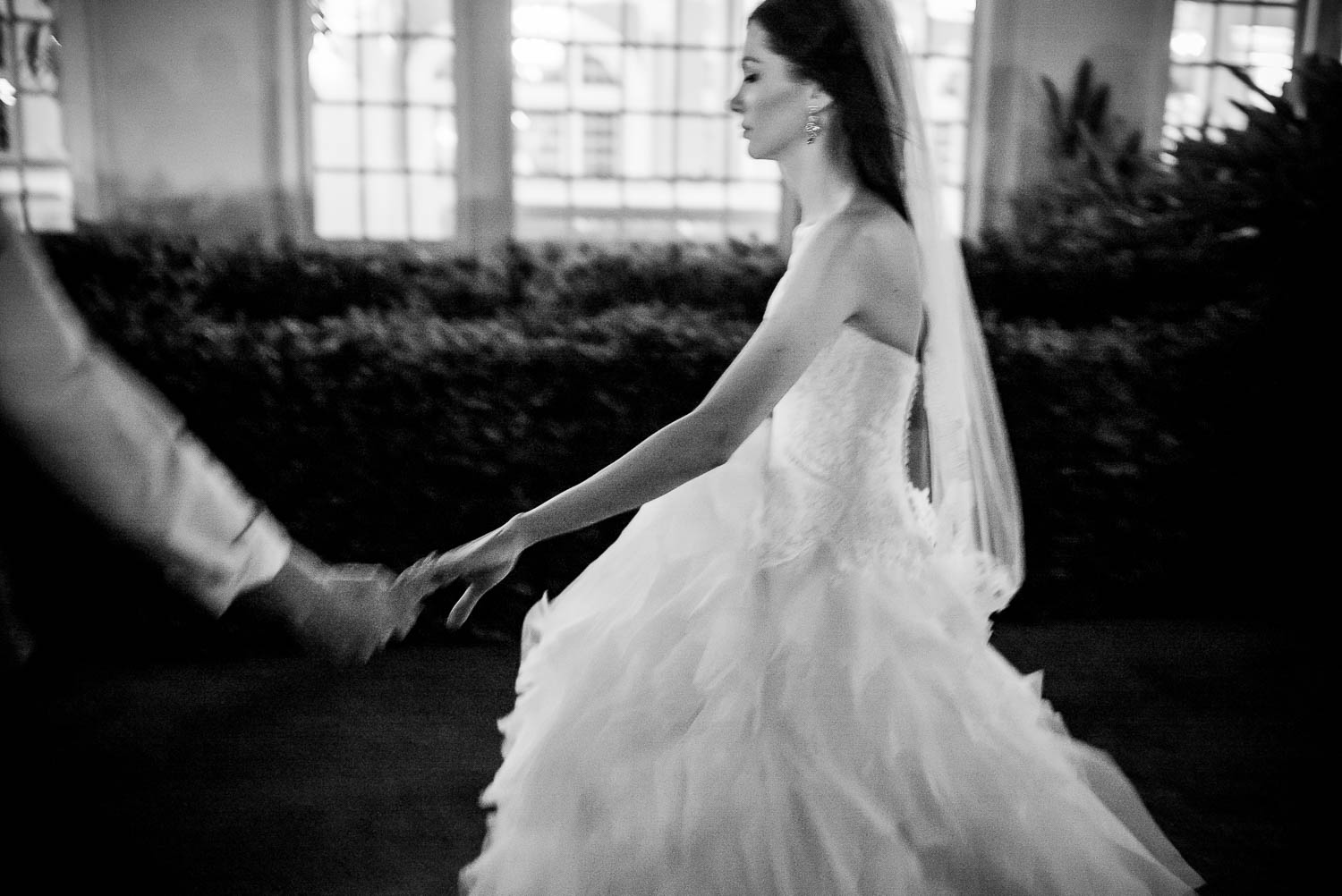 Bride and groom hold hands walking along pathway at an evening wedding reception hotel-galvez-wedding-philip-thomas-photography-028