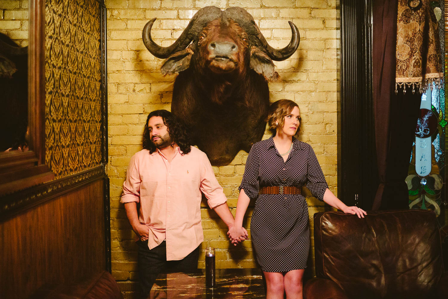 Couples engagement shoot at Junipar Tar a old bar in San Antonio, Texas with a wild buffalo head setting the photo in a triangular structure