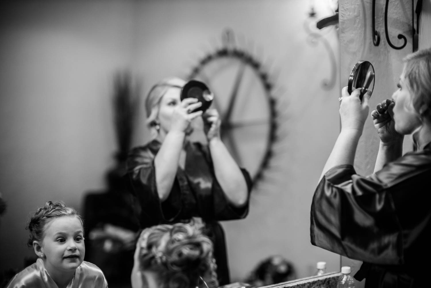 Flower girl looks in mirror as bridesmaids apply makeup at The Springs Boerne-Leica Wedding photographer-Philip Thomas