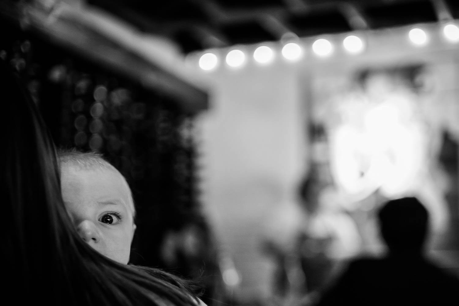 During a wedding rehearsal dinner in Spring, Maryland, a little boy peeks out over his fathers shoulder
