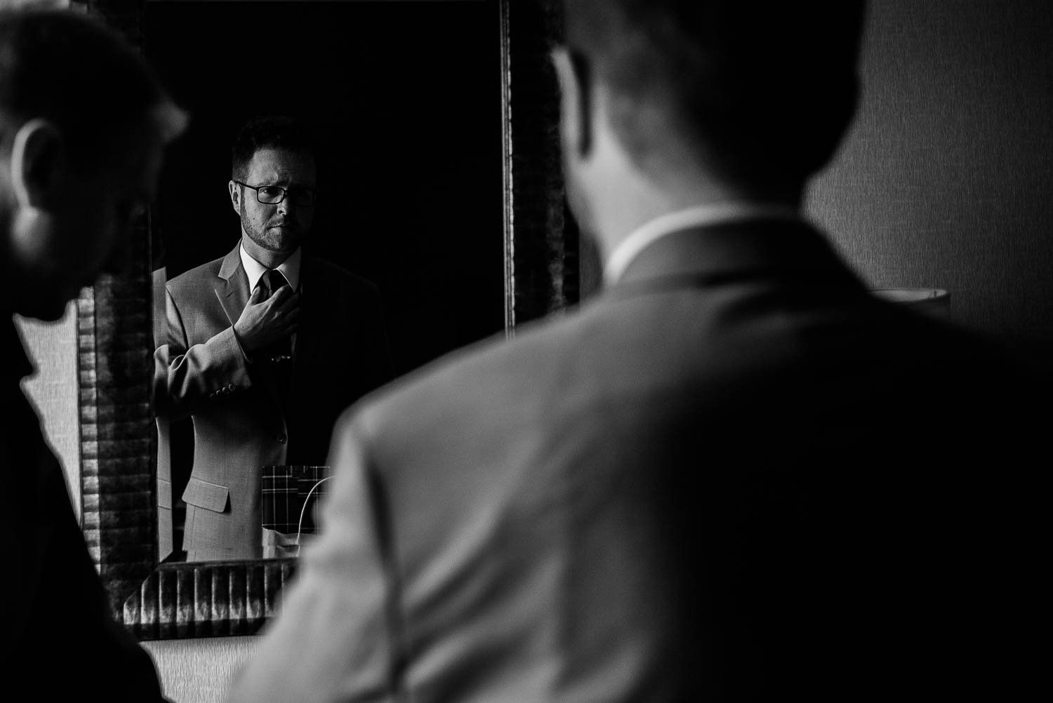 Groom fixes his tie in hotel room mirror, Takoma Park, Washington DC Wedding