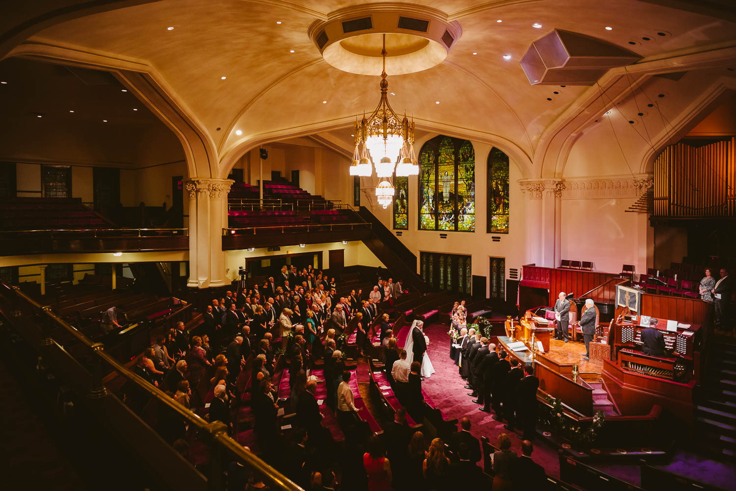 Wide angle photo of wedding ceremony at First United Methodist Church. Brides stands with her father.