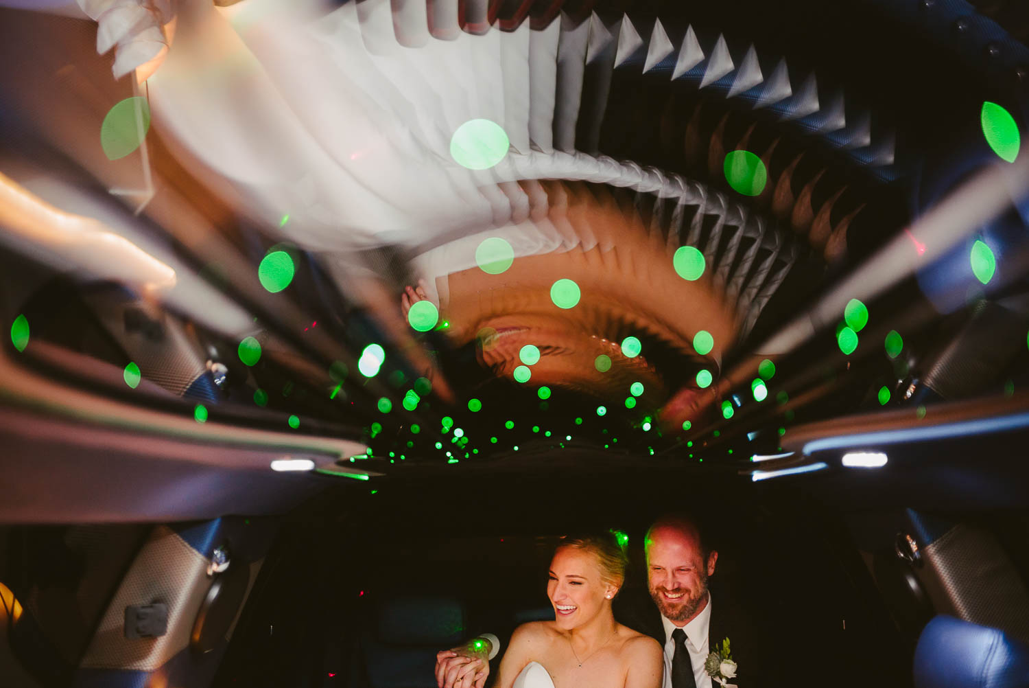 San Antonio wedding photographer capture Couple share a funny moment inside a limo with green sparkling lights Houston Texas en route to Brennan's of Houston, Texas.