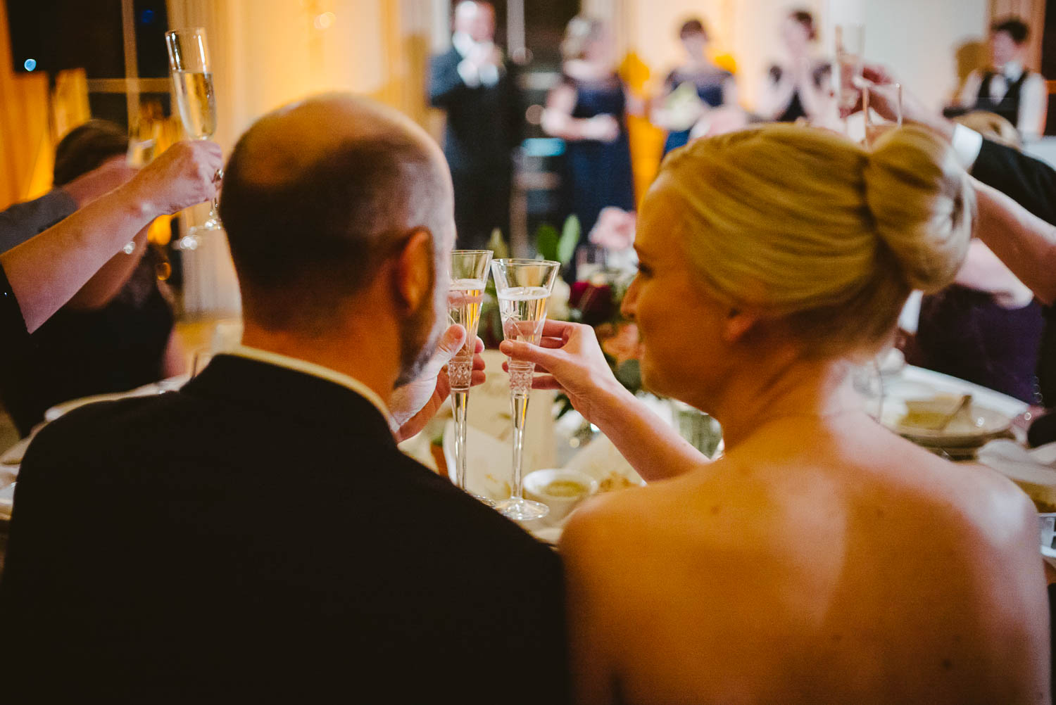 Bride and groom in a close up shot raise their glasses in a wedding toast wedding reception Brennan's of Houston, Texas.