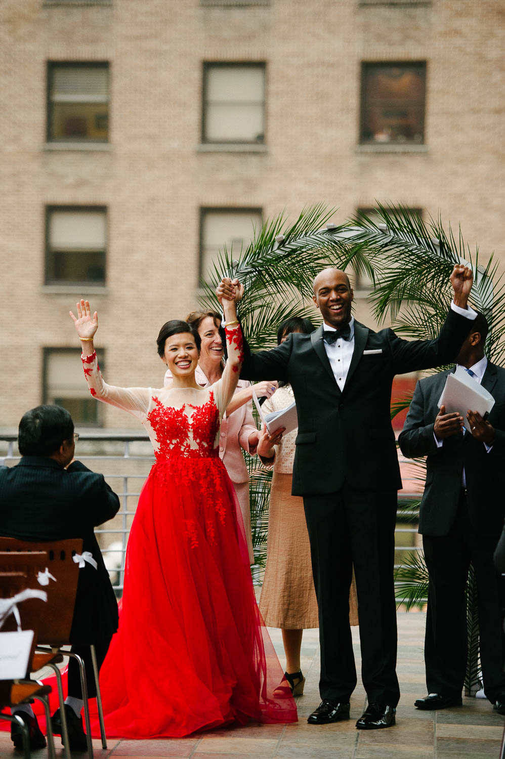 Couple raise their hands in unison as they turn tp face the crowd at a wedding at La Orilla Del Rio Ballroom-Leica photographer-Philip Thomas Photography