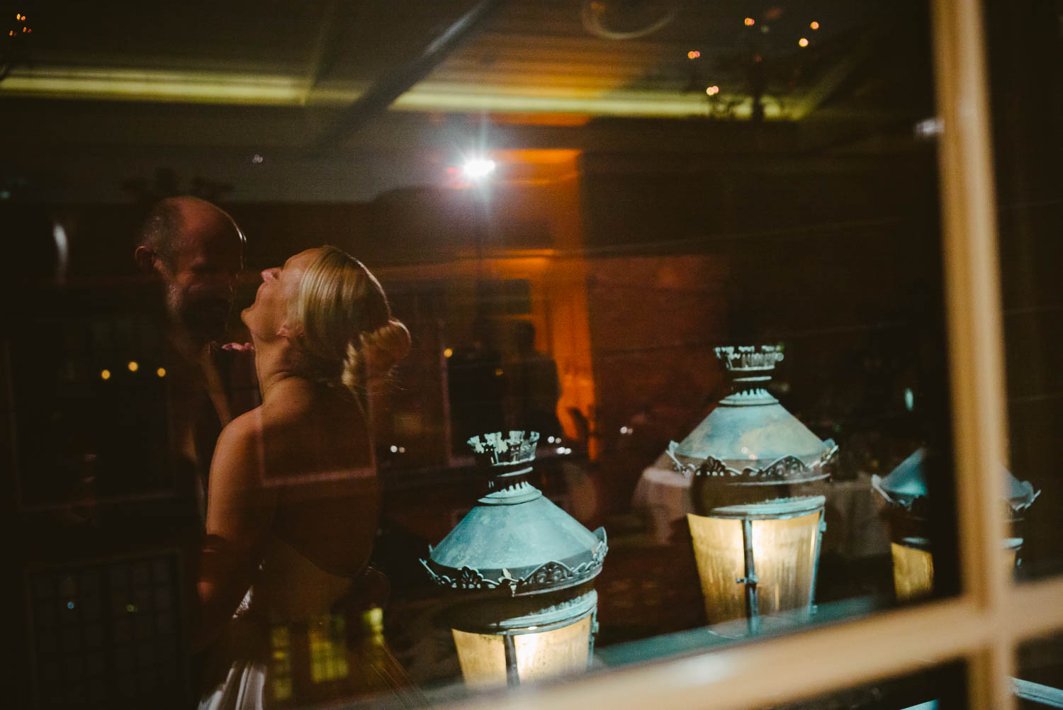 The newly married couple first dance reflect in a glass window wedding reception Brennan's of Houston, Texas.