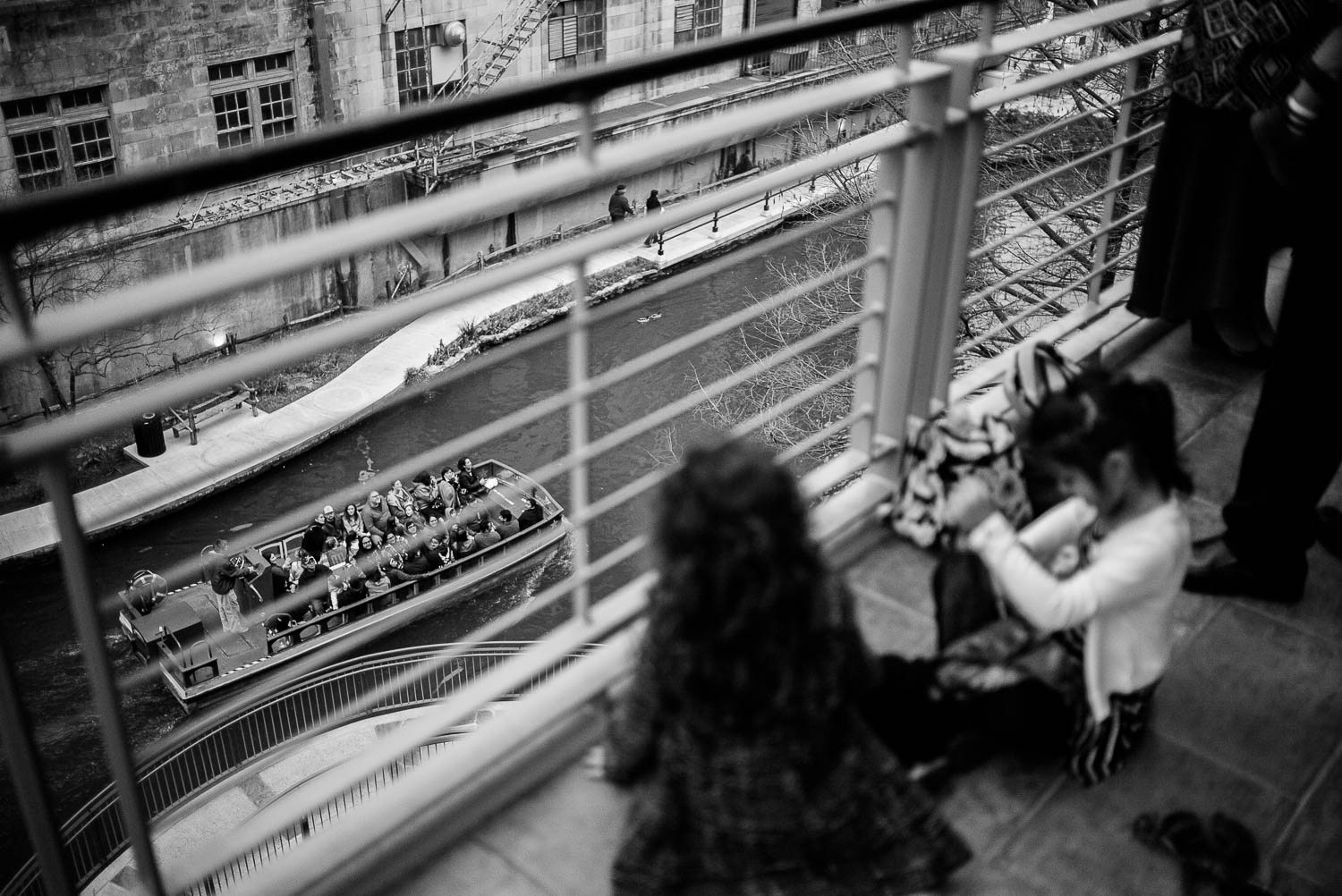 Kids playing at La Orilla Del Rio Ballroom overlook a river barge with tourists below -Leica photographer-Philip Thomas Photography