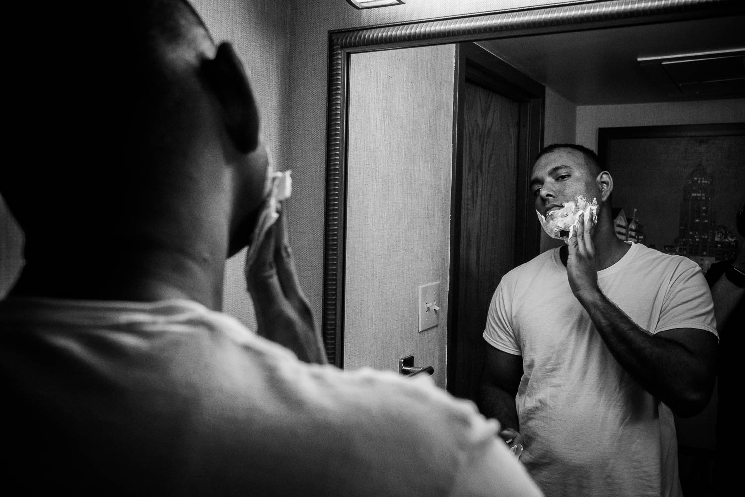 The groom applies shaving cream to his face as he gets ready for his wedding day