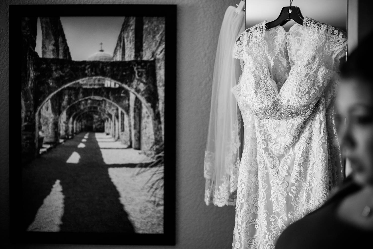 A wedding dress hangs at Drury Inn and Suites, San Antonio as bridesmaids enters the frame in San Antonio Texas
