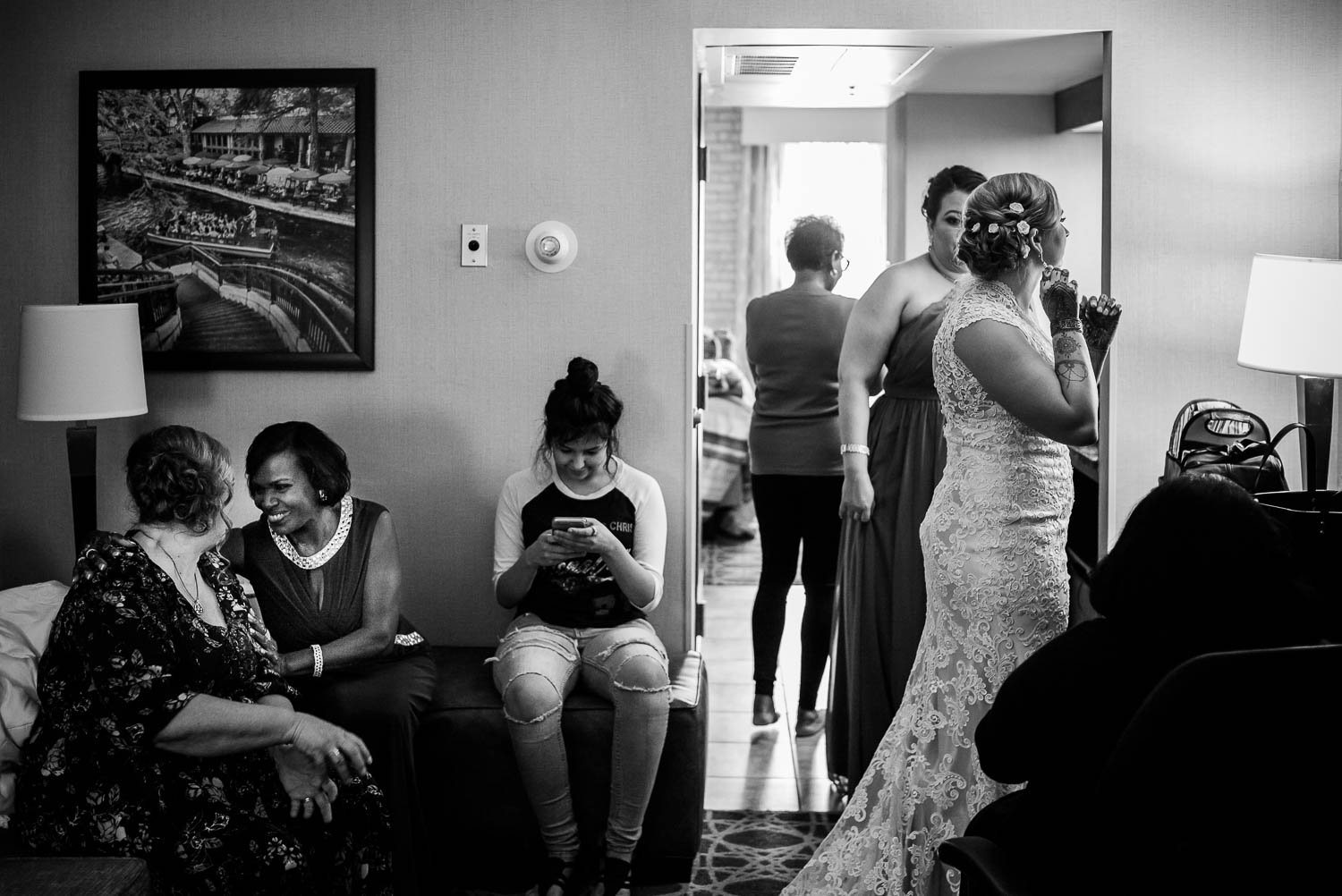Mothers of the bride and groom share a story as bride look in mirror at Drury Inn San Antonio Texas