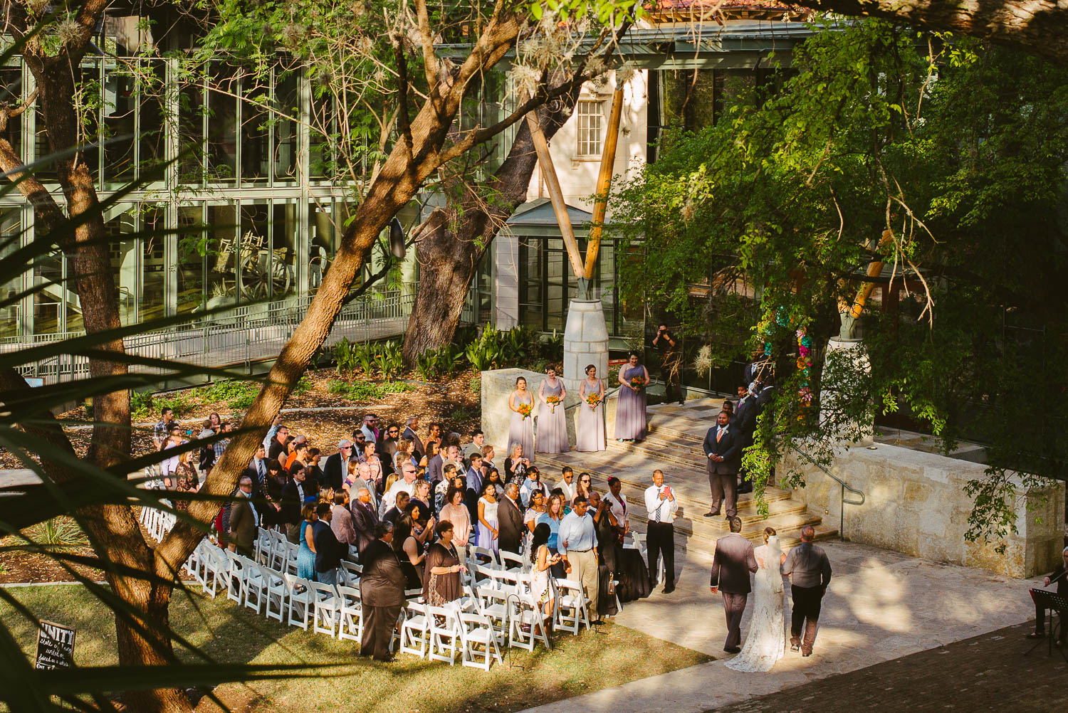 Bride walks down the aisle with father and step father at The Witte Museum San Antonio Texas