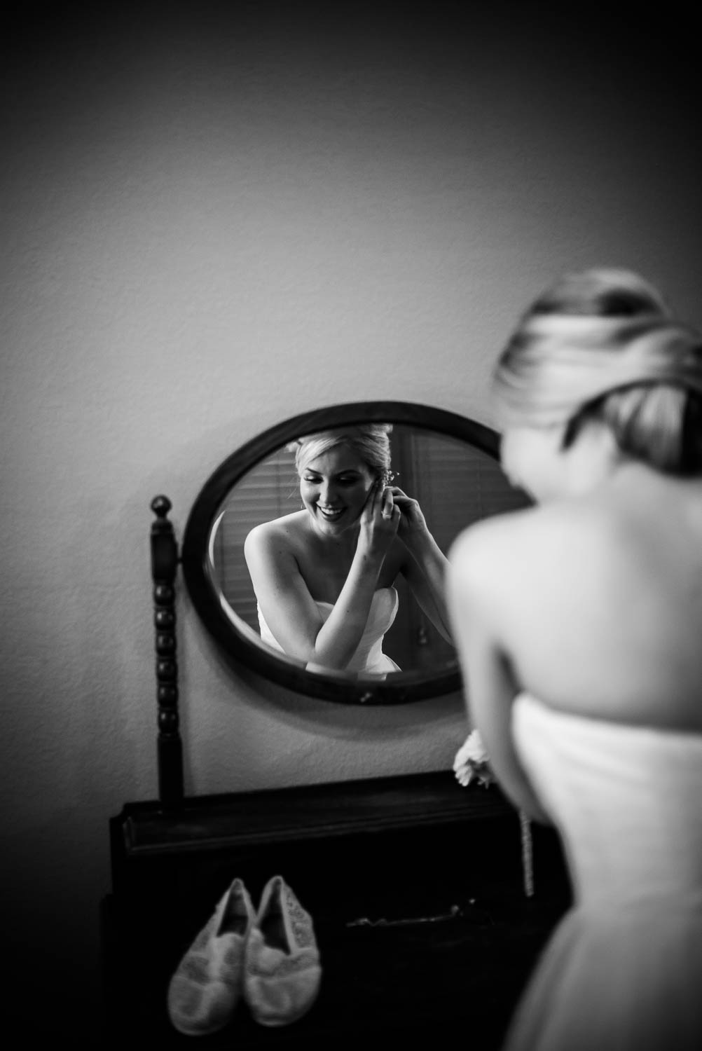 Bride add earrings in mirror at The Gardens of Old Town Helotes Hill Country Wedding